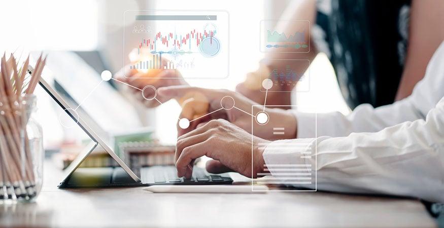 hands typing on laptop with graphs and charts